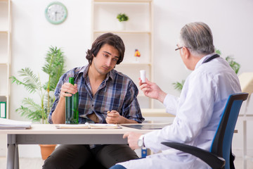 Fototapeta premium Young male alcoholic visiting old doctor