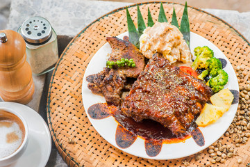  Steak topped with black pepper sauce on a white plate on a wooden table