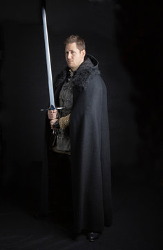 Medieval  Or Post Apocalyptic Man In Leather Jerkin And Cloak Wielding A Sword And Dagger