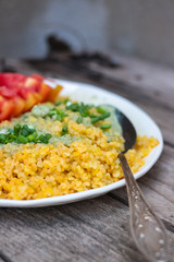 Bulgur with sauce, greens, tomatoes on plate. Vegan lunch.