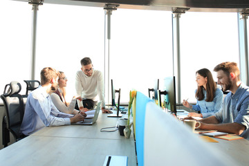 Young modern colleagues in smart casual wear working together while spending time in the creative office.