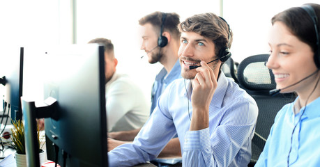 Portrait of call center worker accompanied by his team. Smiling customer support operator at work.