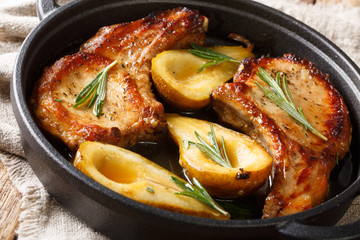 Holiday recipe for baked pork chops with pears and rosemary in honey sauce served in a pan close-up. horizontal