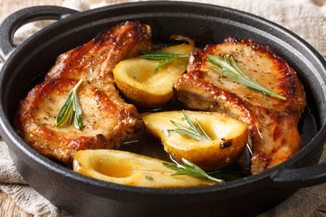 Fried pork chops with ribs with pears and rosemary in honey sauce served in a pan close-up. horizontal