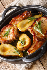 Tasty hot pork chops baked with pears and rosemary in honey sauce in a pan close-up. vertical