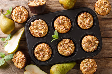 Healthy breakfast pear muffins with walnuts and oatmeal in a baking dish close-up. Horizontal top view