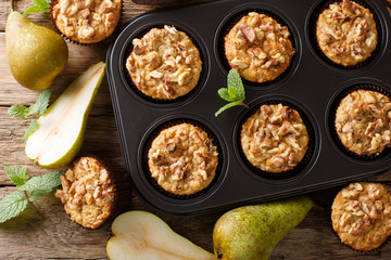 Dietary delicious pear muffins with walnuts and oatmeal in a baking dish close-up. Horizontal top view