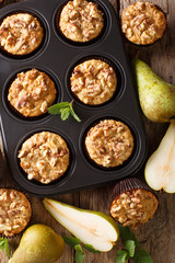 pear muffin with cinnamon and walnuts in a baking dish close-up. Vertical top view