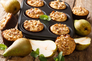 Healthy breakfast pear muffins with walnuts and oatmeal in a baking dish close-up. horizontal