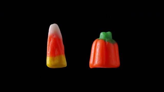 Two pieces of Halloween candy are seen floating and rotating with a black background.