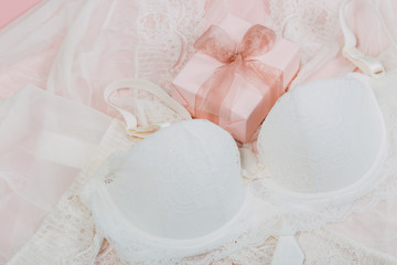 White women underwear with lace and gift box on beige background. white bra and pantie.Copy space. Beauty, fashion blogger concept. Romantic lingerie for Valentine's day temptation. Erotic concept.