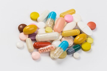 Assorted pharmaceutical medicine pills, tablets and capsules.Heap of assorted various medicine tablets and pills different colors on white background. Top view.Copy space
