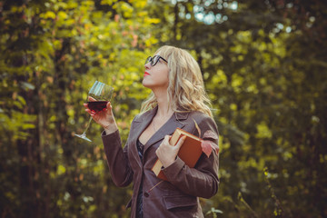 Autumn scene with middle aged plus size woman, glass of wine, fruits and book 