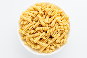 Dried fusili Italian pasta in a round bowl ready to be cooked, isolated on a white table, with view from above 
