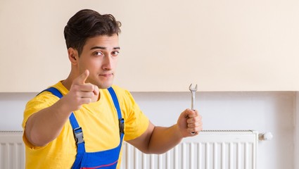 Young repairman contractor repairing heating panel