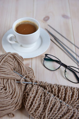 composition of a skein of yarn, glasses, a cup of coffee on a light wooden background