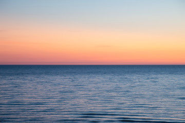 Beautiful Summer landscape sunset image of colorful vibrant sky over calm long exposure sea