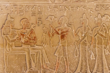 Ancient egyptian paintings and hieroglyphs carved on the stone wall