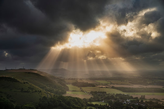 Stunning Summer landscape image of escarpment with dramatic storm clouds and sun beams streaming down