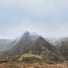 Stunning moody dramatic Winter landscape image of snowcapped Y Garn mountain in Snowdonia