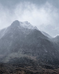 Stunning moody dramatic Winter landscape image of snowcapped Y Garn mountain in Snowdonia