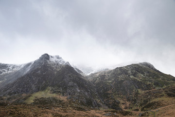 Stunning moody dramatic Winter landscape image of snowcapped Y Garn mountain in Snowdonia