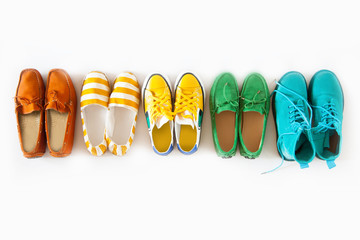 A lot of colored youth women's shoes without heels. Sneakers, slippers, ballet shoes. White background.