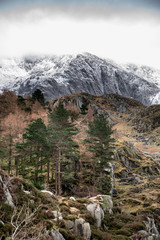 Beautiful moody landscape images of Ogwen Valley in Snowdonia during Winter with snowcapped Glyers mountain range in the background