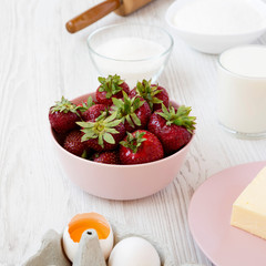 Strawberry pie ingredients: flour, eggs, butter, milk, sugar, strawberry. Side view. Cooking strawberry pie or cake. Copy space.
