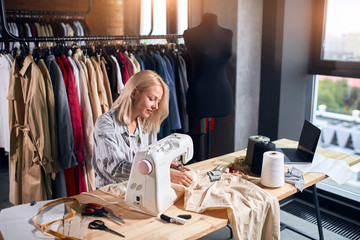 Obraz premium pleasant woman earning money,she sewing clients' clothes. close up photo.