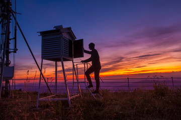 man at weather station in sunset mountain landscape. - obrazy, fototapety, plakaty
