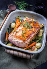 Traditioneller gebratener dry aged Kalbsrücken mit Karotten und Zwiebel angeboten als closeup in einem Topfin a saucepan