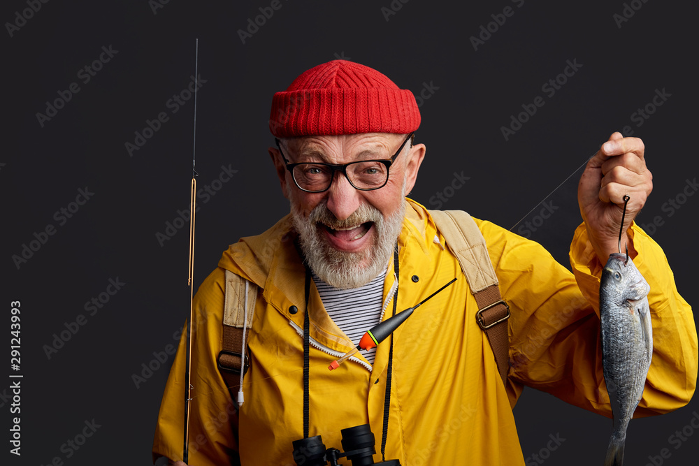 Wall mural funny positive man rejoicing at fish which he has cought in the lake, success and happiness concept.