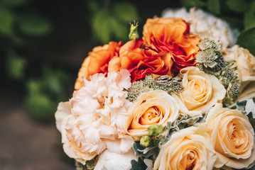 Wedding bouquet made of roses and two wedding rings. Outdoor photo