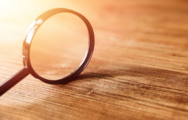 Single Magnifying Glass with Black Handle, Leaning on the Wooden Table.