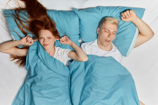 anry nervous woman closing her ears with fingers, being fed up of loud snoring. close up top view photo