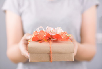 Orange gift box in woman hands for giving in special day