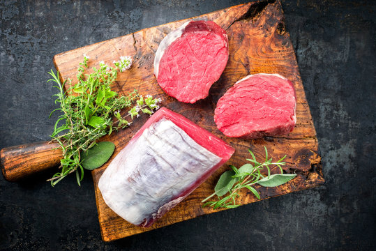 Rohes dry aged Rinderfilet Medaillon Steak natur angeboten als Draufsicht auf einem rustikalen Schneidebrett