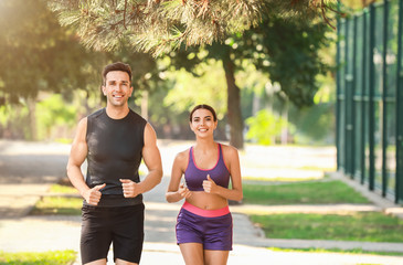 Sporty young couple running in park