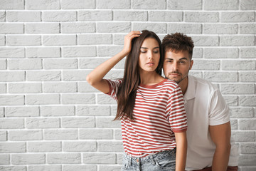 Obraz na płótnie Canvas Fashionable young couple against brick wall