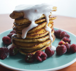 Pancake with flowing yogurt on a blue plate with raspberries