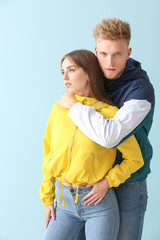 Young couple in stylish sportswear on color background