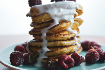 Pancake with flowing yogurt on a blue plate with raspberries