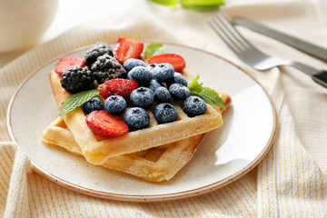 Plate with tasty waffles and berries on table