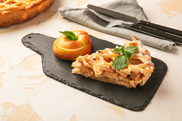Slate plate with piece of tasty apple pie on table
