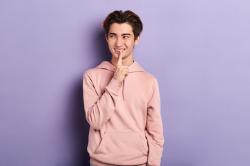 attractive smiling young asian man dressed casually looking aside, touching his lips cunning thoughtful expression, keeping index fingers on his face, trying to recollect something