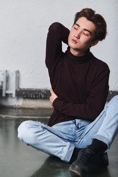 young relaxed man sitting on the floor, massaging his back, neck. close up photo. rest, relaxation