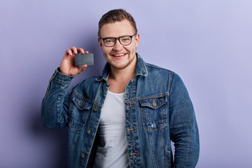 Fototapeta premium smiling brutal guy advertising birthday card, man has bought a card for his girlfriend. gift, close up portrait. isolated blue background, lifestyle