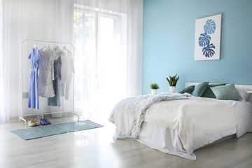 Interior of modern bedroom with big window and clothes rack