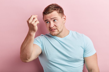 serious strong brutal muscular guy has found grey hairs on his head. close up portrait, isolated pink background, hair care